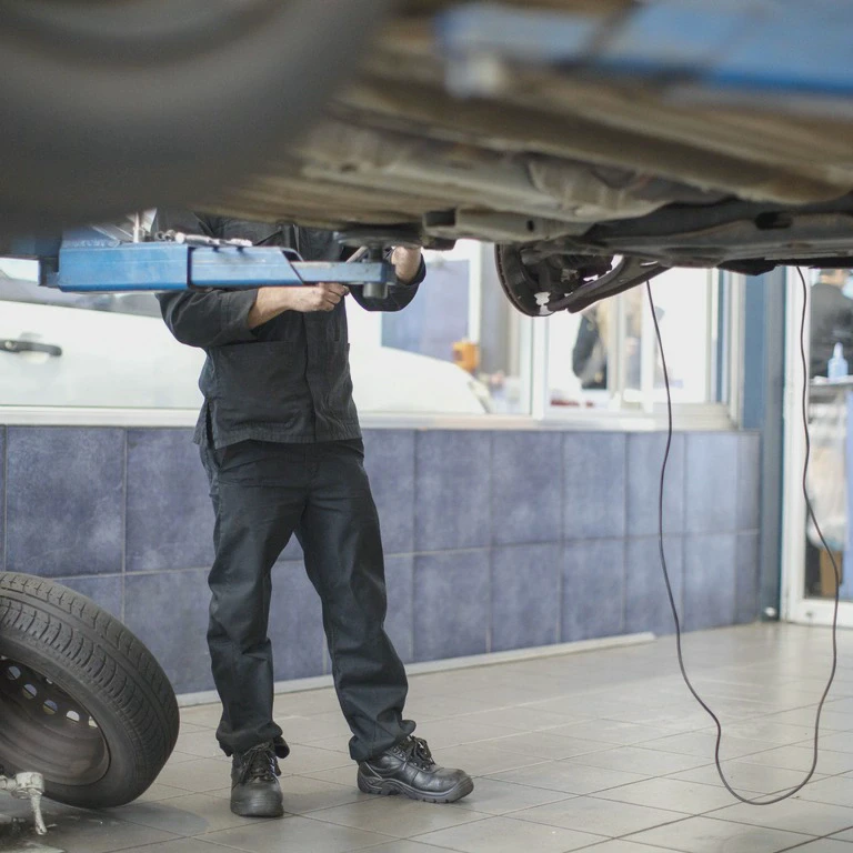 Mechanik naprawiający samochód na podnośniku